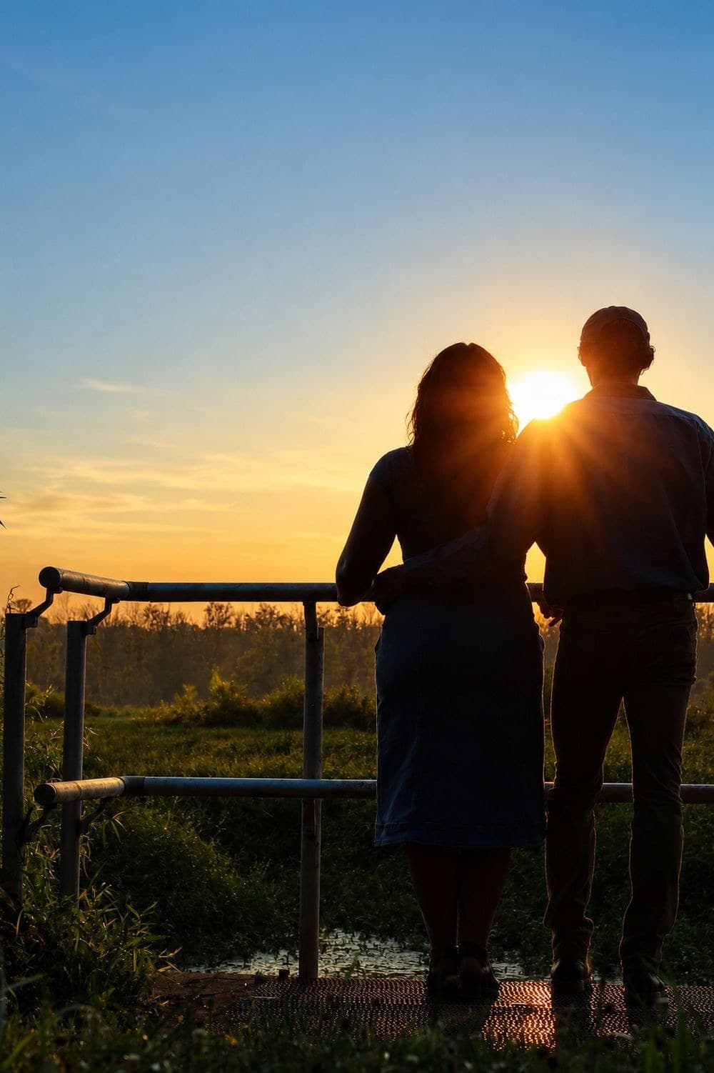 Couple watching the sun set over the fields