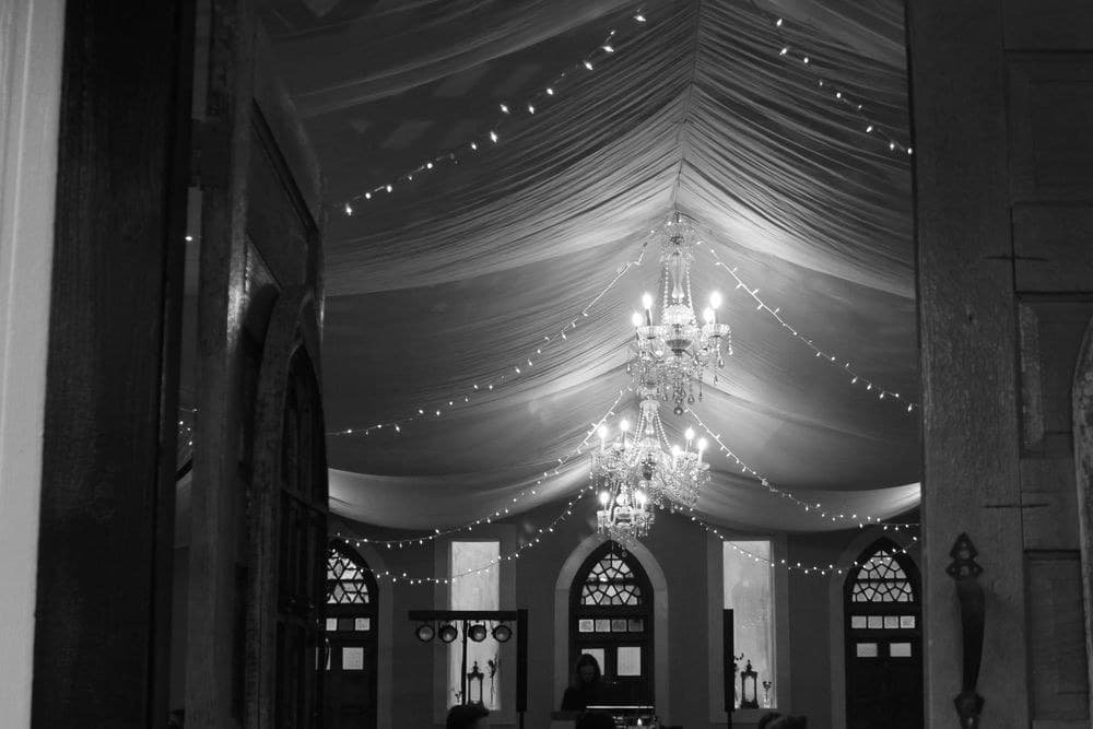A venue dressed in draping and chandeliers, in black and white