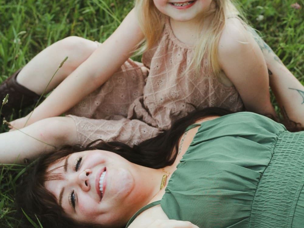 Mom cuddled in the grass with her daughter